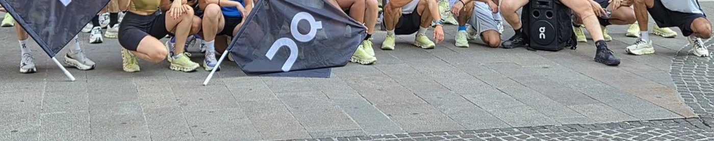 Runners’ shoes and On flags on the pavement outside the On store in Milano